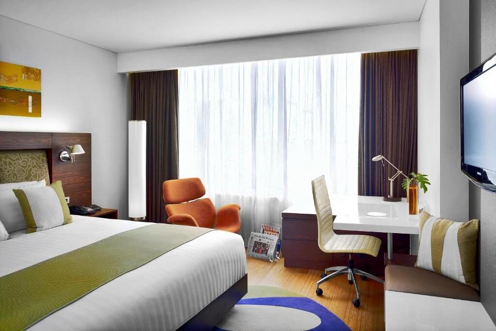 The room at NH Bangkok Asoke is fully equipped with a desk, sofa, and wardrobe.