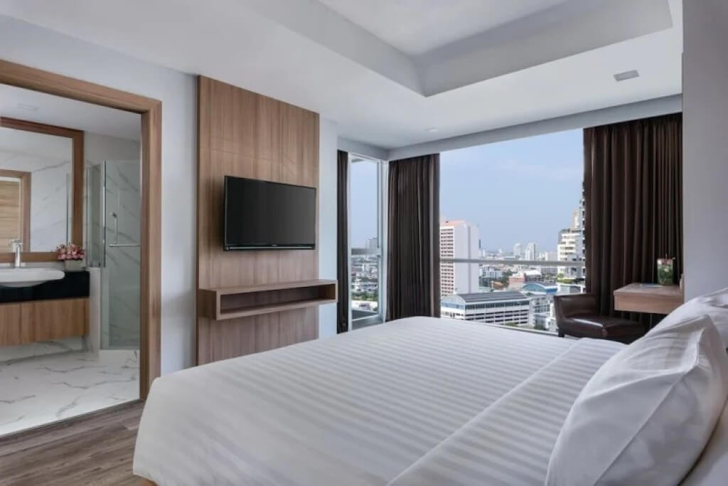 Oakwood Studios Sukhumvit Bangkok One-Bedroom Suite with a double bed, floor-to-ceiling windows, and Bangkok night view.
