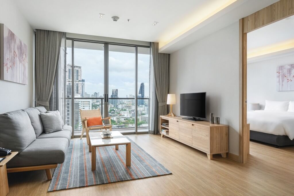Oakwood Suites Bangkok living room with large window and city view