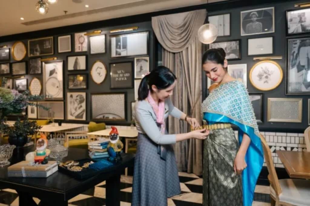 The Salil Hotel Sukhumvit 57 staff helping guest put on traditional Thai costume with accessories