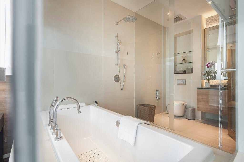 Bathroom with walk-in shower and separate bathtub at MUU Bangkok Hotel
