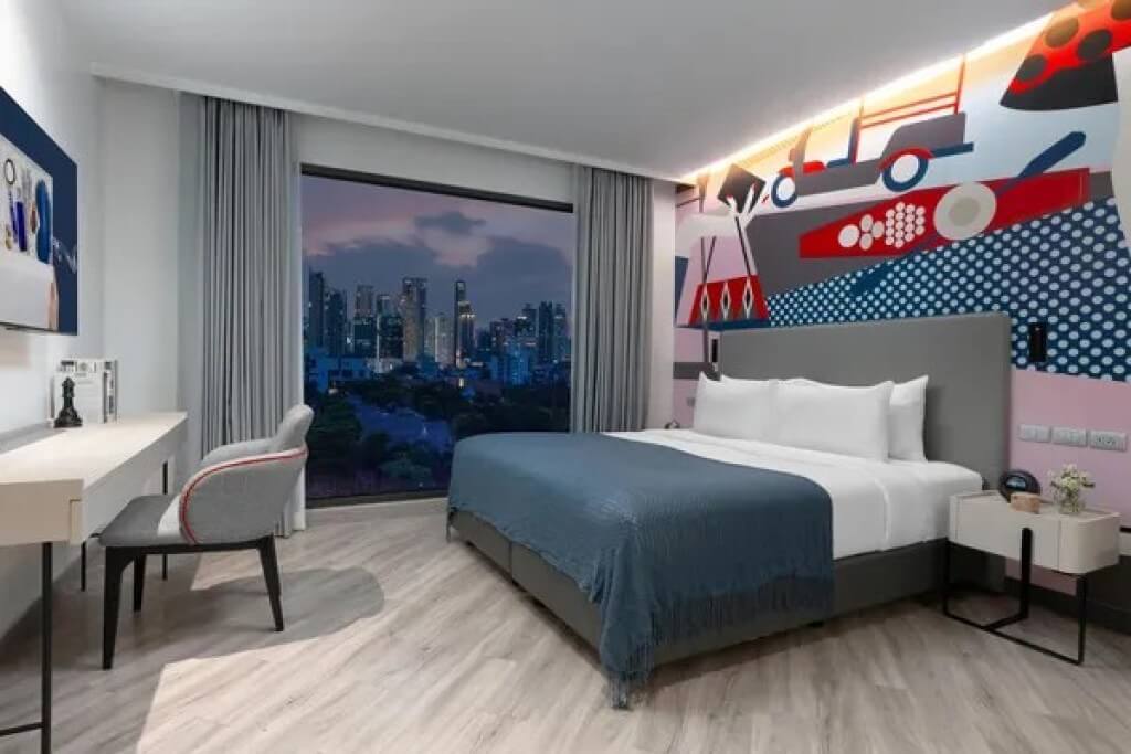 Executive Suite at Oakwood Studios Sukhumvit Bangkok with a double bed, floor-to-ceiling windows, and a night city view.