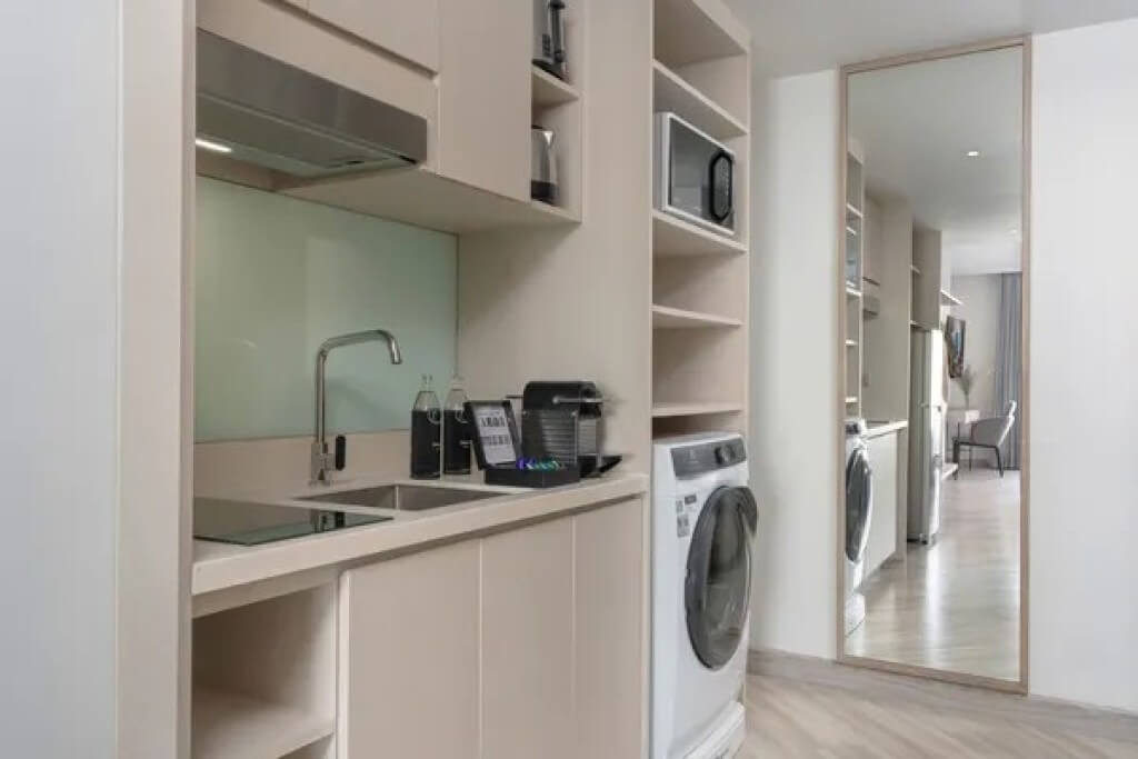 Kitchen in the Executive Suite at Oakwood Studios Sukhumvit Bangkok, featuring a microwave, refrigerator, and washing machine.