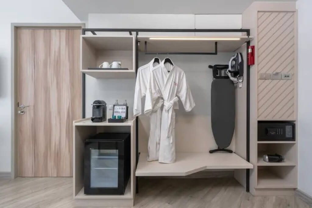 Connecting door to the second bedroom, wardrobe area, and minibar in the Two-Bedroom Suite at Oakwood Studios Sukhumvit Bangkok.