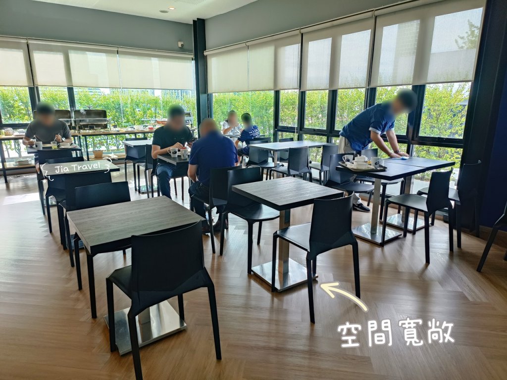 Kokotel Bangkok Sukhumvit 50 bright breakfast seating area surrounded by floor-to-ceiling windows with wooden tables and chairs