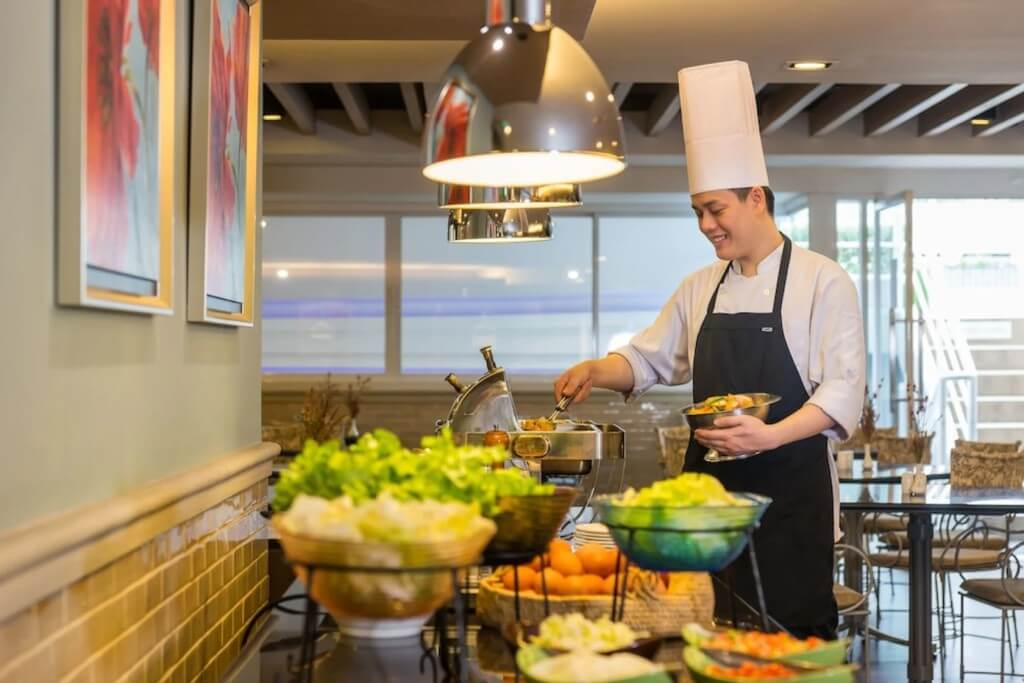 Chef replenishing breakfast buffet at Evergreen Place Siam by UHG